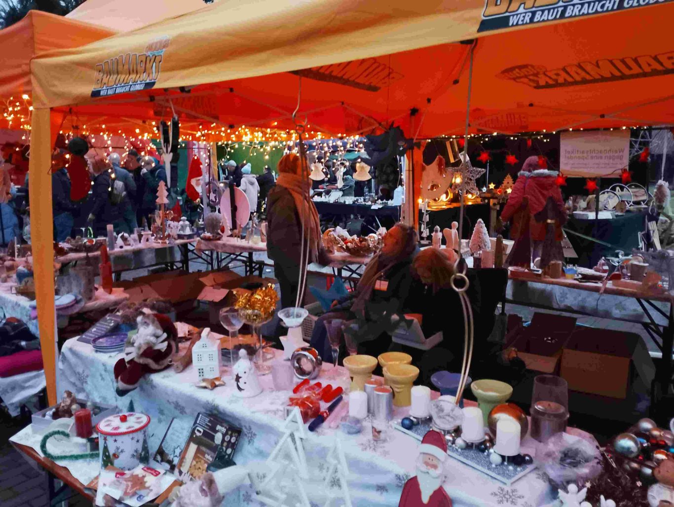 Spendenstand Weihnachtsmarkt Ortsgemeinschaft Brühl-Ost 2025 auf dem Vorplatz St. Stephan Marktstand mit verschiedenen Antiquitäten und Schnäppchen, umgeben von Besuchern.
