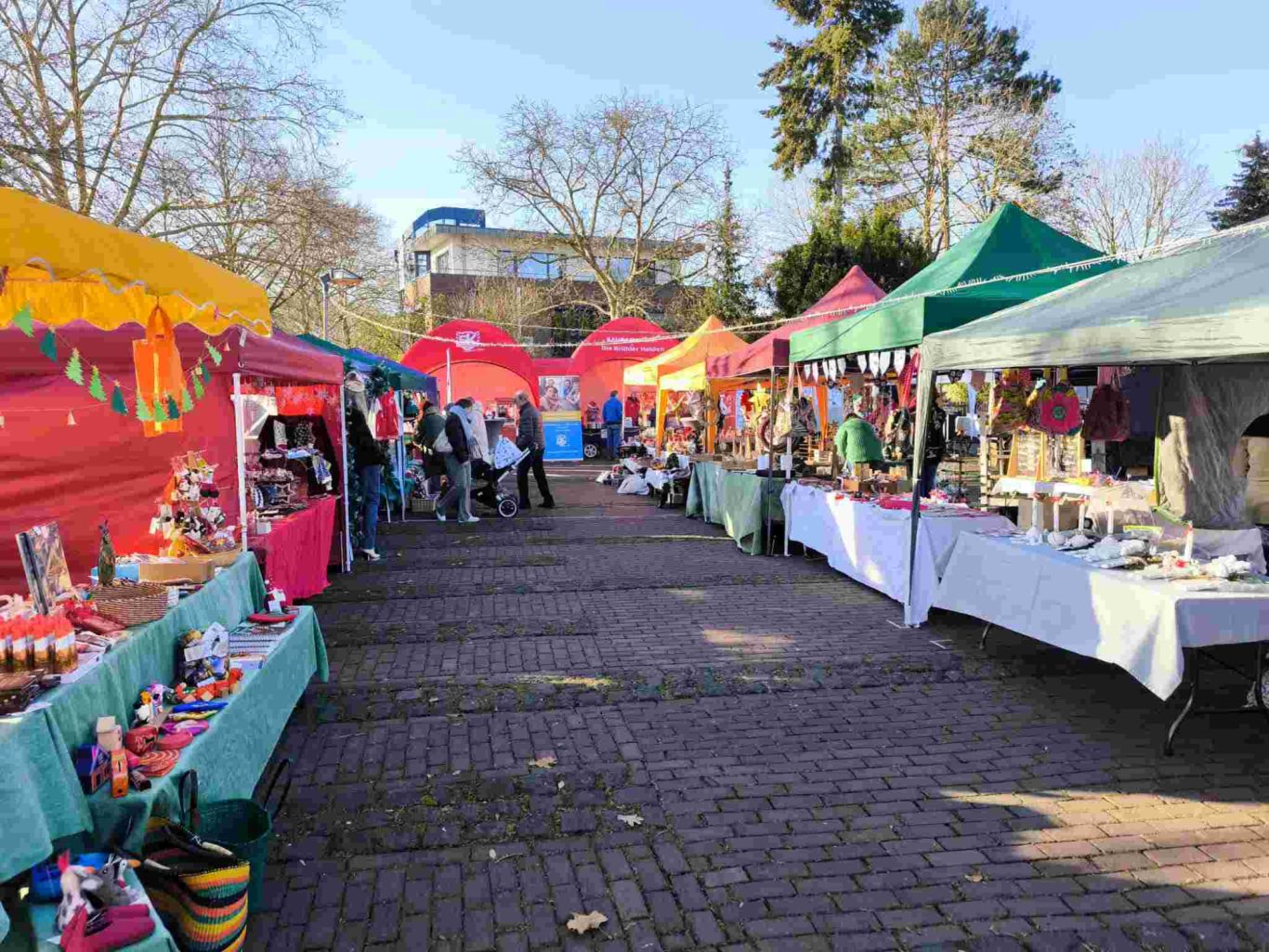 Weihnachtsmarkt Ortsgemeinschaft Brühl-Ost 2025 auf dem Vorplatz St. Stephan Markt mit bunten Ständen, Besuchern und fröhlicher Atmosphäre unter blauem Himmel.