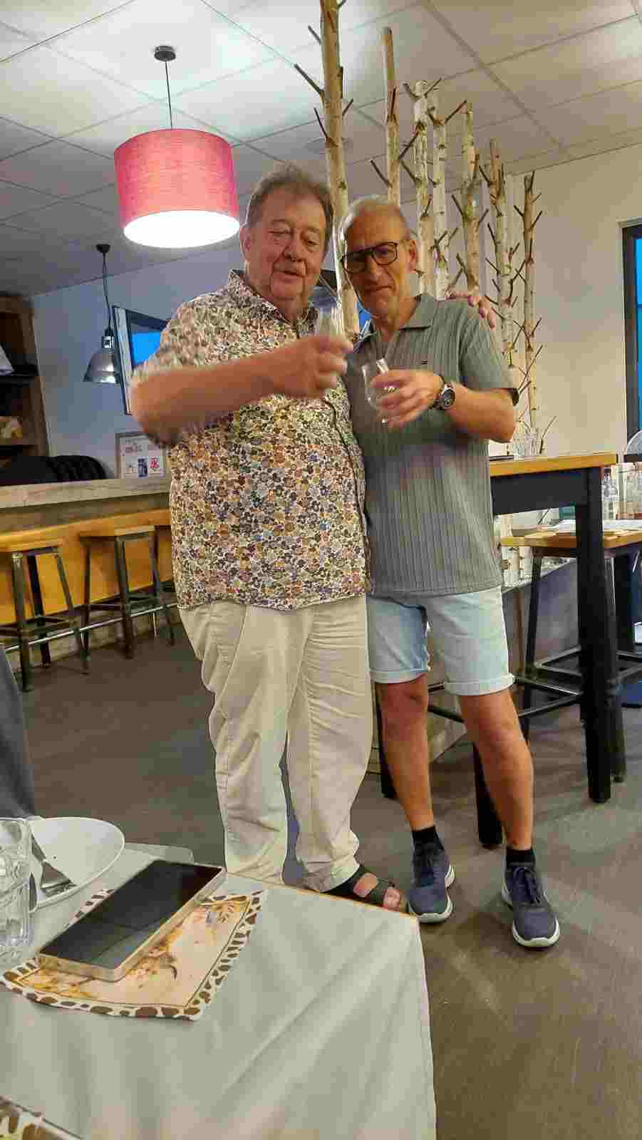 Ortsgemeinschaft Brühl-Ost. Einladung zum Whisky Tasting Zwei Männer stehen in einem Restaurant, beide halten Getränke und lächeln.