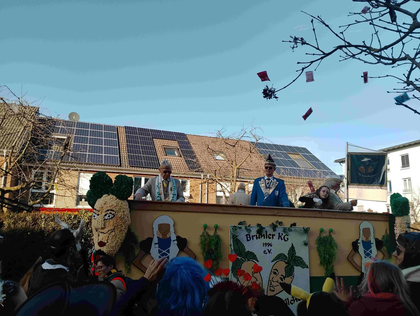 Brühler KG - Karnevalszug in Brühl-Ost 2026 Karnevalswagen mit bunten Figuren und Menschen bei einer Festlichkeit im Freien.